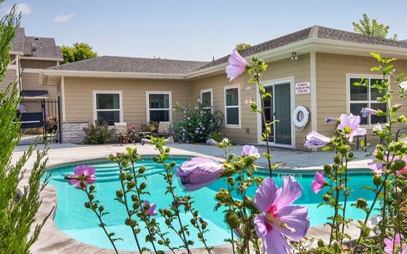 a building with a pool and flowers in front of it